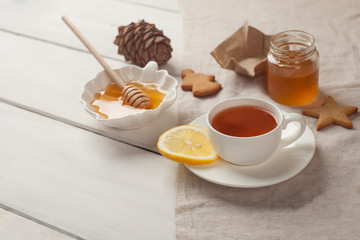 Composition of black tea with lemon, honey and cookies on a white background, copy space