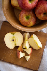 Red apples in a wooden bowl on a wooden background