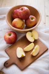 Red apples in a wooden bowl on a wooden background