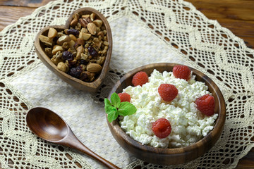 Cottage cheese with fresh raspberry in a wooden bowl on old wooden background with copy space for your text. Top view