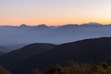 Beautiful dusk over various layers of mountains with orange and blue tones
