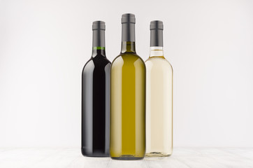 Set wine bottles  different colors - transparent, green, black- on white wooden board, mock up. Template for advertising, design, branding identity.