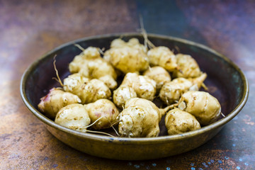 Autumn harvest - Jerusalem artichoke tubers in old bowl.