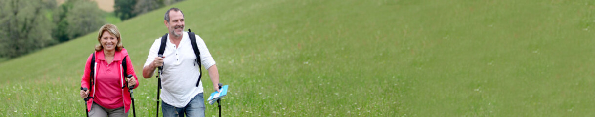 Senior couple hiking in countryside - banner template web