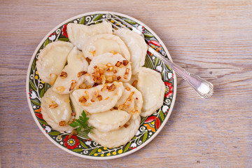 Dumplings, filled with potato and served with salty caramelized onion. Varenyky, vareniki, pierogi, pyrohy - popular dish in East Europe. View from above, top studio shot, horizontal