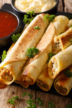 Mexican taquitos with chicken and cheese stuffing close-up, and sauces. vertical