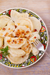 Dumplings, filled with potato and served with salty caramelized onion. Varenyky, vareniki, pierogi, pyrohy - popular dish in East Europe. View from above, top studio shot, vertical