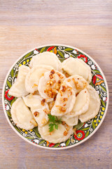 Dumplings, filled with potato and served with salty caramelized onion. Varenyky, vareniki, pierogi, pyrohy - popular dish in East Europe. View from above, top studio shot, vertical