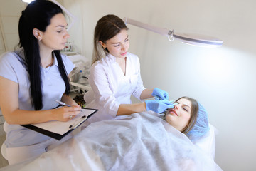 Girl of permanent tattoo artist demonstrates to female student h