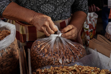 Woman selling fresh unpeeled nuts on a market stall
