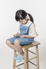Fototapeta na wymiar pretty asian girl hand holding a digital device(smart phone) sitting with stool isolated white