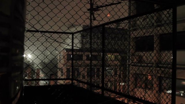Night rain in Bangkok. View on wet street from balcony through rabitz net. Thailand.