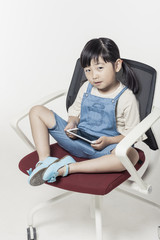 pretty asian girl hand holding a digital device(smart phone), sitting a chair isolated white