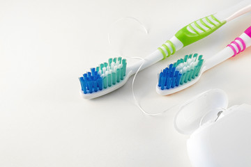 Toothbrushes and dental floss on white background