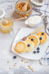 curd cheese cakes and granola with honey, yogurt, sour cream and milk