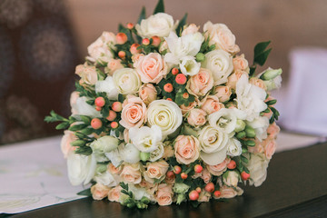 Wedding bouquet of small white and pastel pink roses and berries.