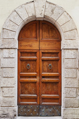 Old wooden brown door in a gray stone wall Rome, Italy