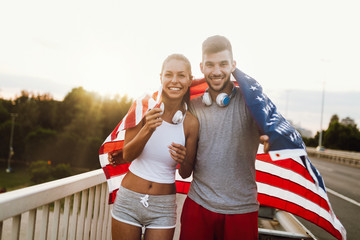 Portrait of attractive fitness couple holding American flag
