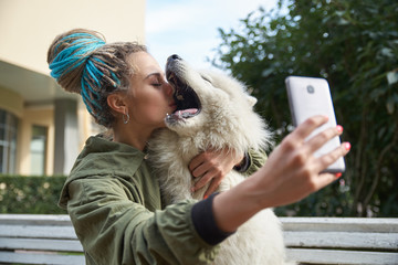 young girl in green coat and multicolored dreadlocks makes a selfie on your smartphone posing with...