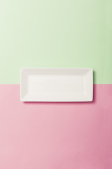 white empty square dish on the color(green, pink) paper background.