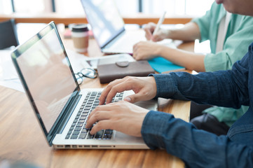 Young hipster worker typing on laptop keyboard in office