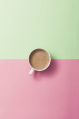 A cup of coffee on the color(green, pink) paper background.