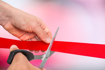 Hand with scissors cutting red ribbon - opening ceremony
