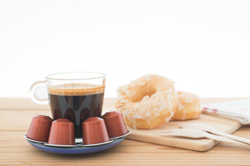 Cup of espresso, espresso capsule and bakery on wooden table.