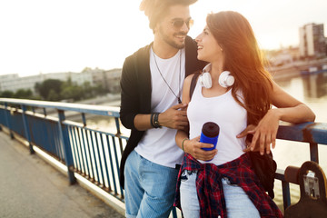 Picture of young attractive couple carrying skateboards