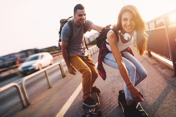 Young attractive couple riding skateboards and having fun