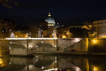 Illuminated Ponte Vittorio Emanuele II bridge at night with the dome of St Peter's Basilica in the distance, in Rome, Italy