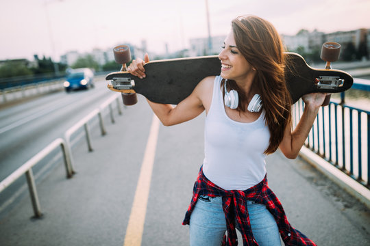 Portrait of beautiful smiling girl carrying skateboard