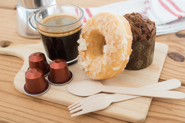 Cup of espresso, espresso capsule and bakery on wooden table.