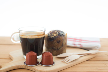 Cup of espresso, espresso capsule and bakery on wooden table.