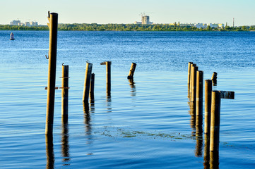 Wooden posts for the berth of boats and boats on the reservoir