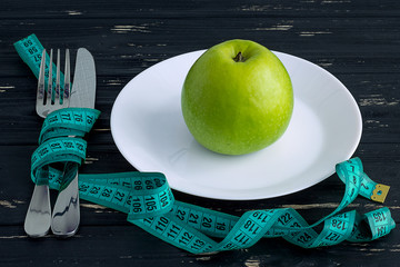 Apple on the plate with measuring tape on the wooden background
