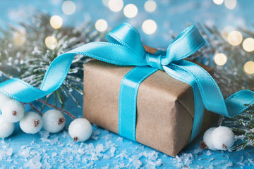 Christmas or new year composition with gift box and snowy fir tree on turquoise bokeh background....