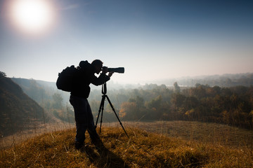 Silhouette of photographer taking landscape photos in morning.