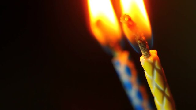 Various birthday candles close up while burning down. Macro clip.