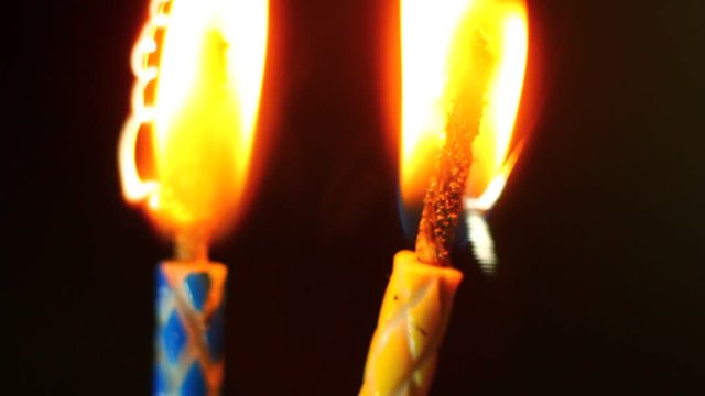 Various birthday candles close up while burning down. Macro clip.