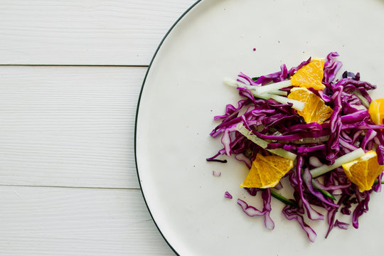 Red cabbage salad with orange on white dish