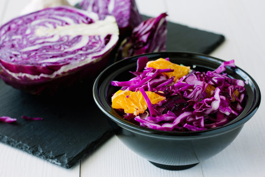 Red cabbage salad with orange in black bowl