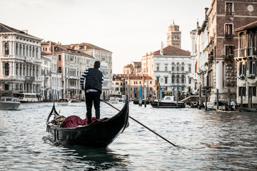 Fototapeta na wymiar Italian street on water, Beautiful nooks in Venice, Night view of canal in venice, Man on gondola in Venice, Young man in boat carrying tourists in Italy, Venetian taxi on water