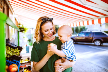 Young mother with her baby boy at outdoor market.