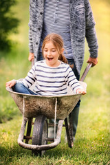 Grandfather pushing his grandaughter in a wheelbarrow.