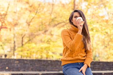 Stylish girl drinking coffee in autumn park