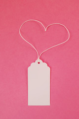 White blank paper price tag or label on the pink background, top view.