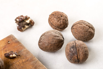 Wooden board and walnuts for cleaning above white marble background table