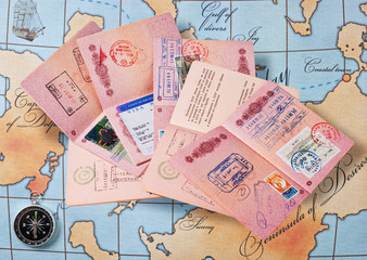 a stack of passports on a map and compass