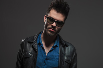 Obraz premium hot man in leather jacket and sunglasses poses